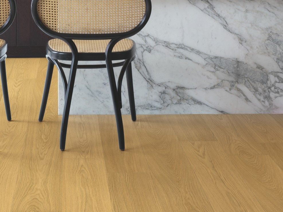 light brown Quick-Step laminate flooring in a modern kitchen with a quartz waterfall island and black wooden bistro chairs